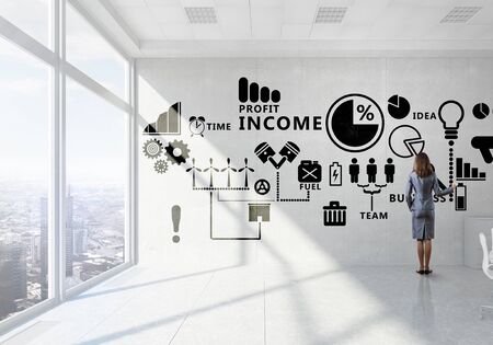 Elegant businesswoman in modern office interior against window panoramic view drawing on bannerの写真素材