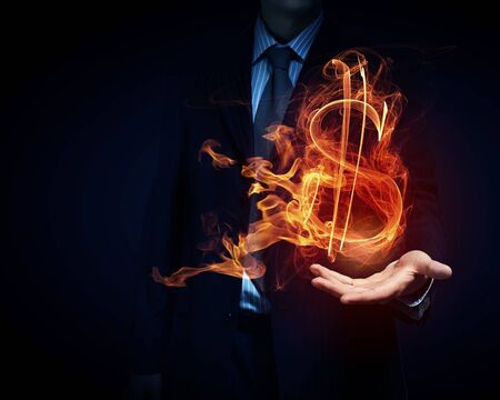 Burning dollar sign in businessman palm on dark backgroundの写真素材