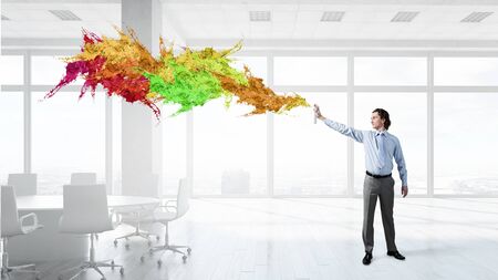 Concept of creativity with businessman in office spraying paint from balloonの写真素材