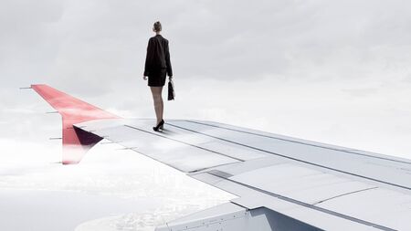 Young businesswoman standing on edge of airplane wing