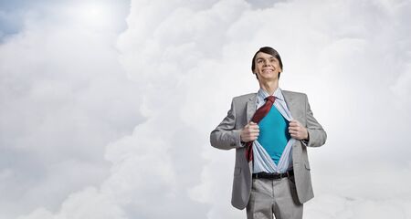 Young smiling businessman acting like super hero and tearing his shirt offの写真素材