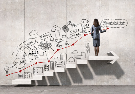 Businesswoman drawing strategy plan over ladder leading to successの写真素材