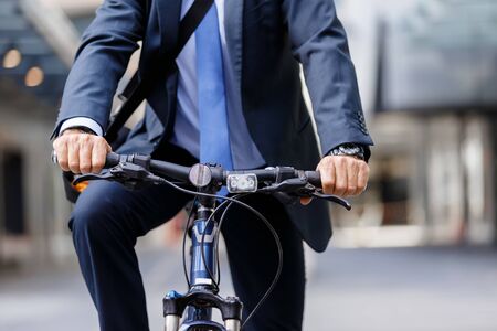 Successful businessman in suit riding bicycleの写真素材