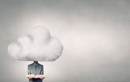Young businessman with book in hands and cloud instead of headの写真素材