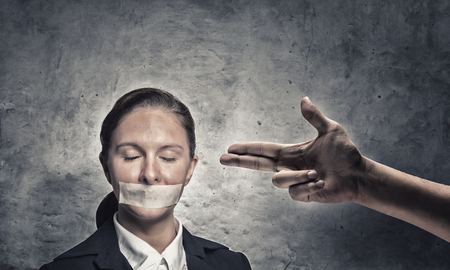 Young speechless businesswoman with adhesive tape on mouthの写真素材