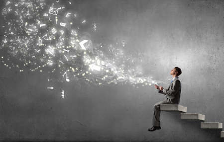 Young businessman sitting on steps with mobile phone in handの写真素材