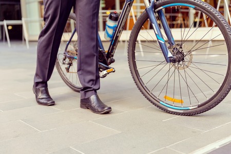 Successful businessman in suit with bicycle in cityの写真素材