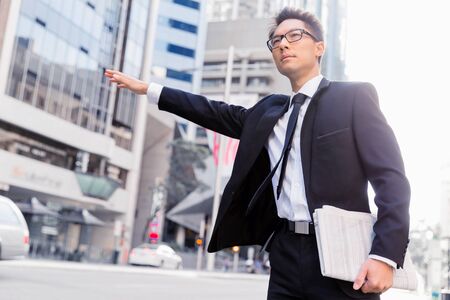 Businessman trying to catch a taxi in business cuty districtの写真素材