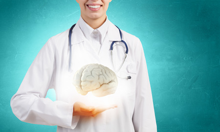 Woman doctor in white holding human brain in palms