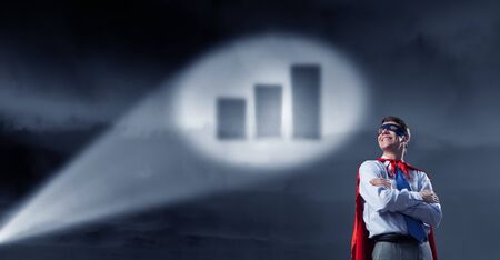 Young confident super businessman in mask and cape at nightの写真素材