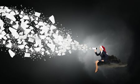 Santa businesswoman sitting on cloud and shouting into megaphoneの写真素材