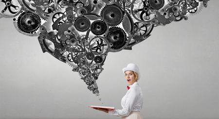 Young woman in white hat with opened book in hands and gears flying outの写真素材