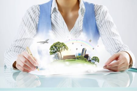 Close view of businesswoman writing with pen and urban landscape on papersの写真素材