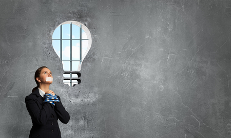 Young speechless businesswoman with tied hands and adhesive tape on mouthの写真素材