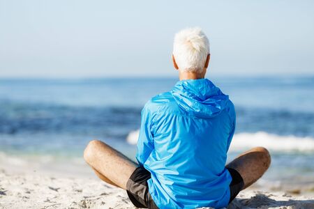Handsome caucasian male doing exercises on beachの写真素材