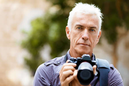 Senior man with camera in cityの写真素材