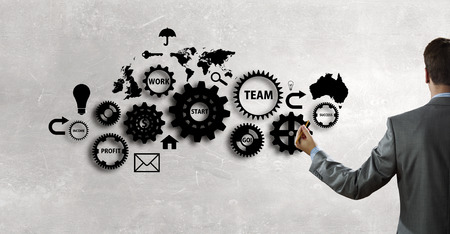 Back view of businessman standing with back and drawing gears mechanismの写真素材