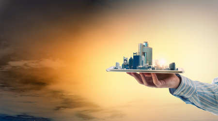 Hand holding tablet computer with cityscape on screen