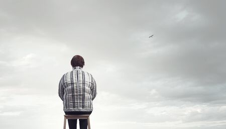 Back view of plus size woman sitting on chairの写真素材