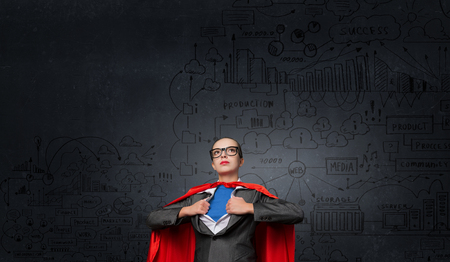 Businesswoman wearing red cape and opening her shirt like superheroの写真素材