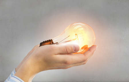 Close up of hand holding glowing light bulbの写真素材