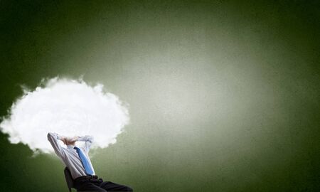 Young businessman sitting in chair and cloud instead of headの写真素材