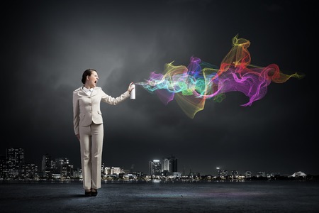 Young businesswoman in glasses using spray balloonの写真素材