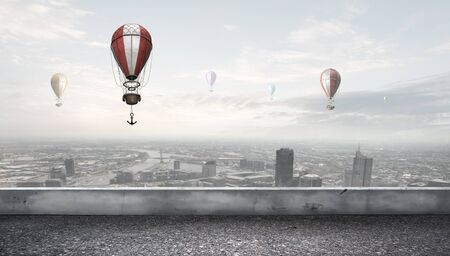 Colorful aerostats flying in clear sky above modern cityの写真素材