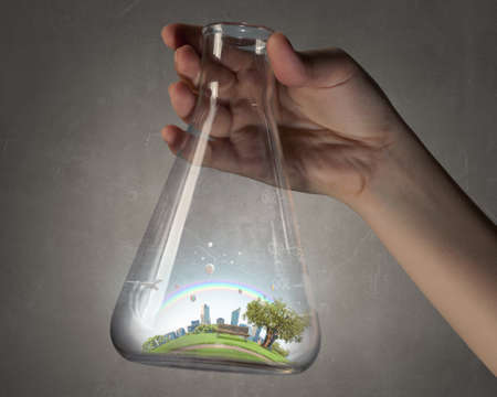 Hand holds flask with image of green life concept