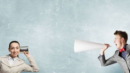 Young pretty businesswoman attaching tin phone to earの写真素材