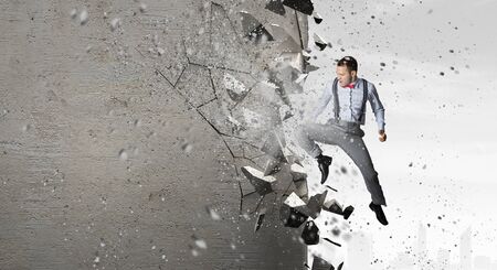 Emotional businessman breaking stone wall with karate punchの写真素材