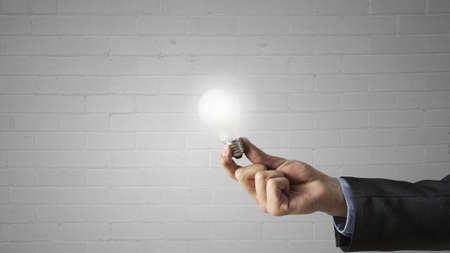 Glowing light bulb in person hand throwing light on darkness