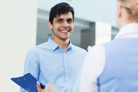 Businessman and woman in modern interior holding document case and talking to her colleagueの写真素材