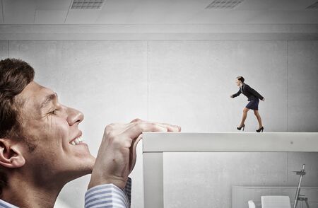 Young man looking from under table on running businesswomanの写真素材