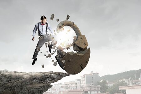 Young angry businessman crashing stone lock with handの写真素材