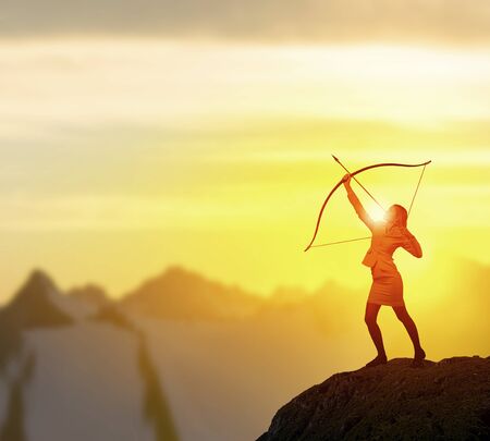 Young woman archer in suit aiming to make shootの写真素材