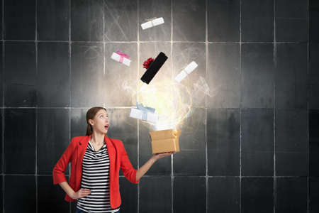 Happy young woman in red jacket opening gift boxの写真素材