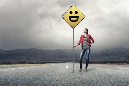 Young girl in red jacket on road showing roadsignの写真素材