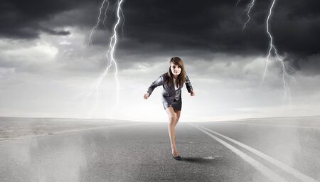 Young determined businesswoman on road standing in start position