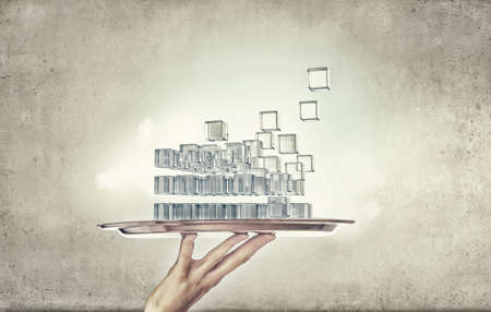 Hand holding metal tray with digital cube figureの写真素材