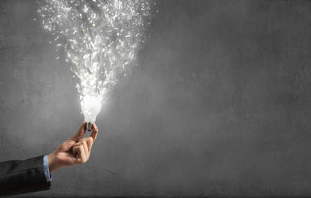 Glowing light bulb in person hand throwing light on darknessの写真素材