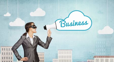 Unrecognizable businesswoman hiding her face behind mask and screaming in megaphoneの写真素材