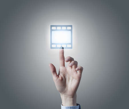 Close up of hand touching video icon on media screen