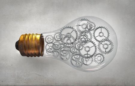 Glass light bulb with gears inside on concrete backgroundの写真素材