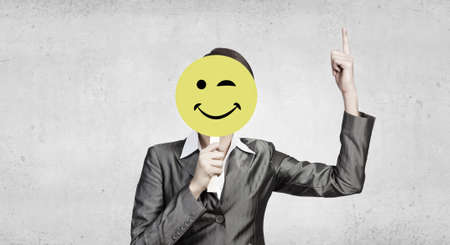Businesswoman in suit hiding her face behind maskの写真素材