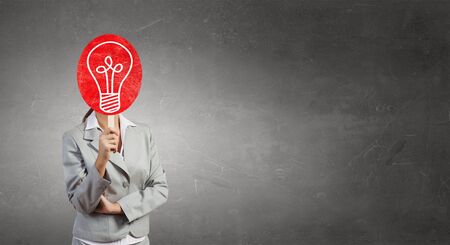 Unrecognizable businesswoman hiding her face behind carton cardの写真素材