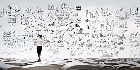 Back view of businesswoman drawing business strategy sketch on wallの写真素材