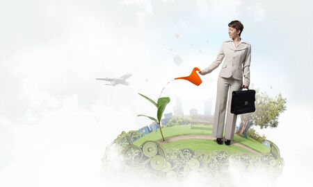 Businesswoman with can watering green growing money treeの写真素材