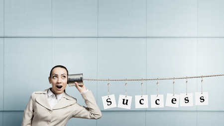 Young pretty businesswoman attaching tin phone to earの写真素材