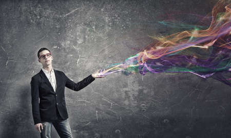 Young man in red glasses and colorful lights from his handの写真素材